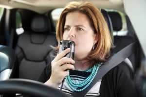 a woman in a car blowing into a Smart Start ignition interlock