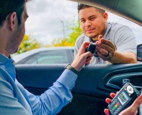 a man in car holding out an ignition interlock to a service agent