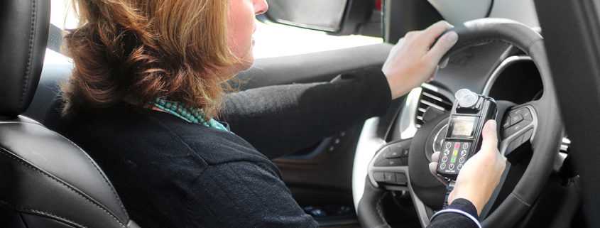 Customer holding an Ignition Interlock Device in car
