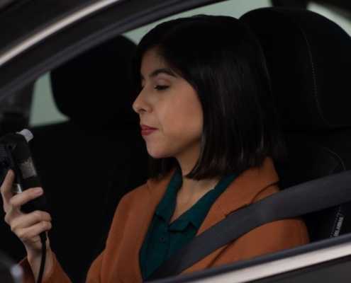 A woman driver prepares to blow into a car breathalyzer