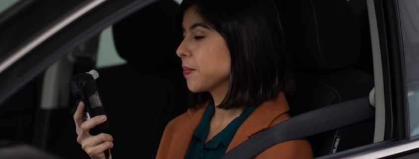 A woman driver prepares to blow into a car breathalyzer
