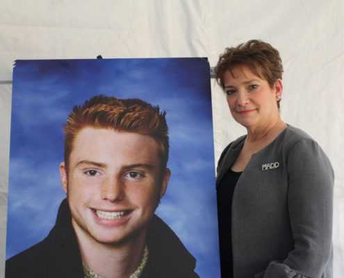 Colleen Sheehey-Church of Mothers Against Drunk Driving with a poster photo of her son Dustin