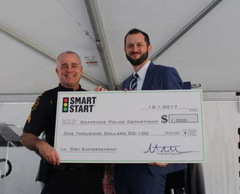 Smart Start CEO Matt Strausz presents a check for 1,000 dollars to the Grapevine Police Department