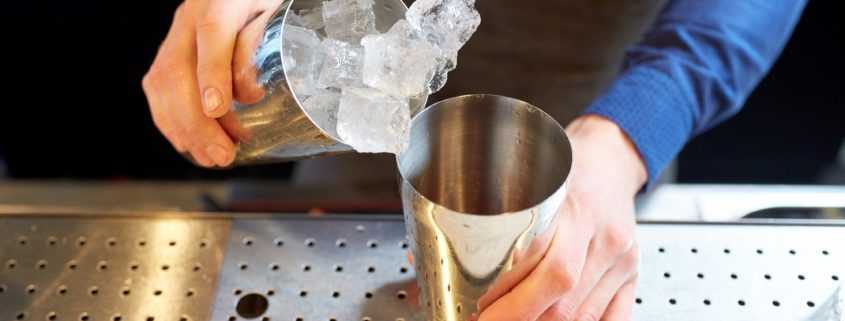 Bartender prepares drink using ice and shaker