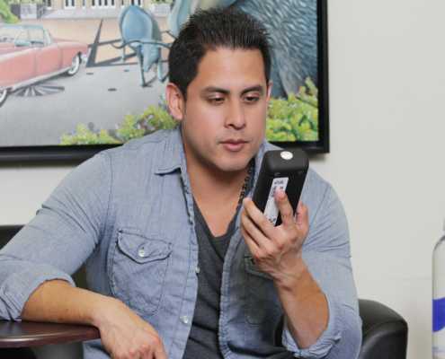 Photo of Man Holding SMART Mobile Device in a Room