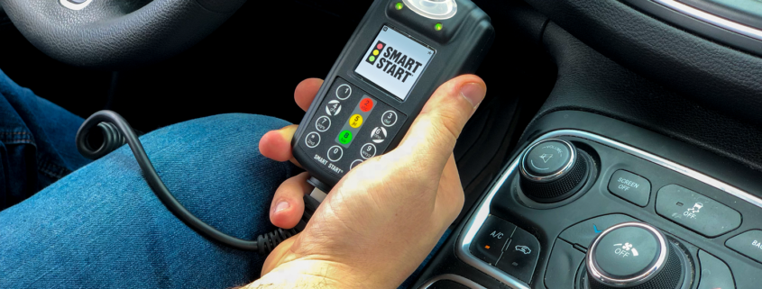 Customer Holding A Smart Start Ignition Interlock Device in car