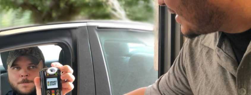 Smart Start Technician hands Ignition Interlock Device customer in car