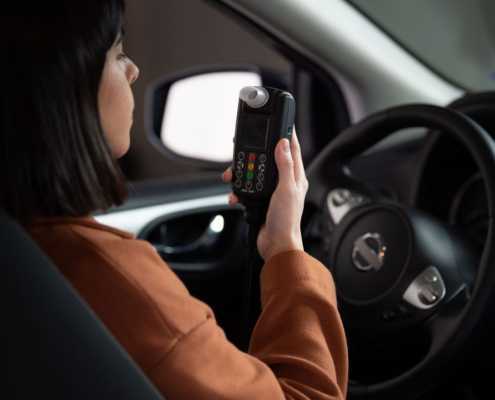 A woman uses a Smart Start Ignition Interlock Device before starting her car.