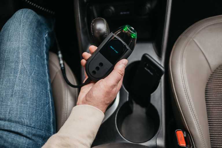 a person holding a Smart Start FLEX™ ignition interlock in a car
