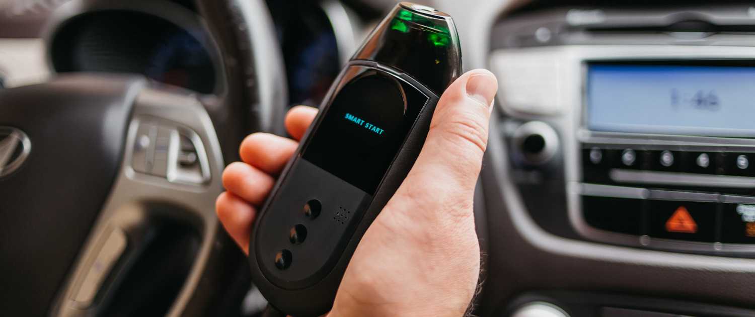 a hand holding a Smart Start FLEX™ with a screen on in a car