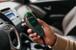 a person holding a a Smart Start FLEX™ ignition interlock in a car