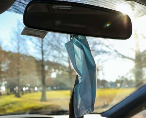 a blue mask hanging from the rear-view mirror in a car