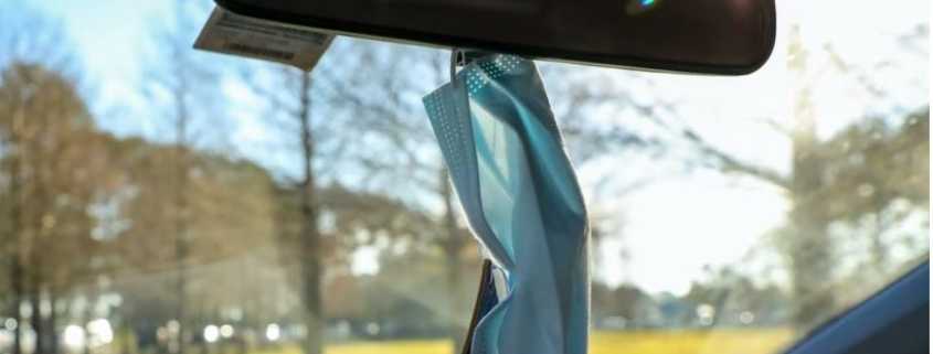 a blue mask hanging from the rear-view mirror in a car